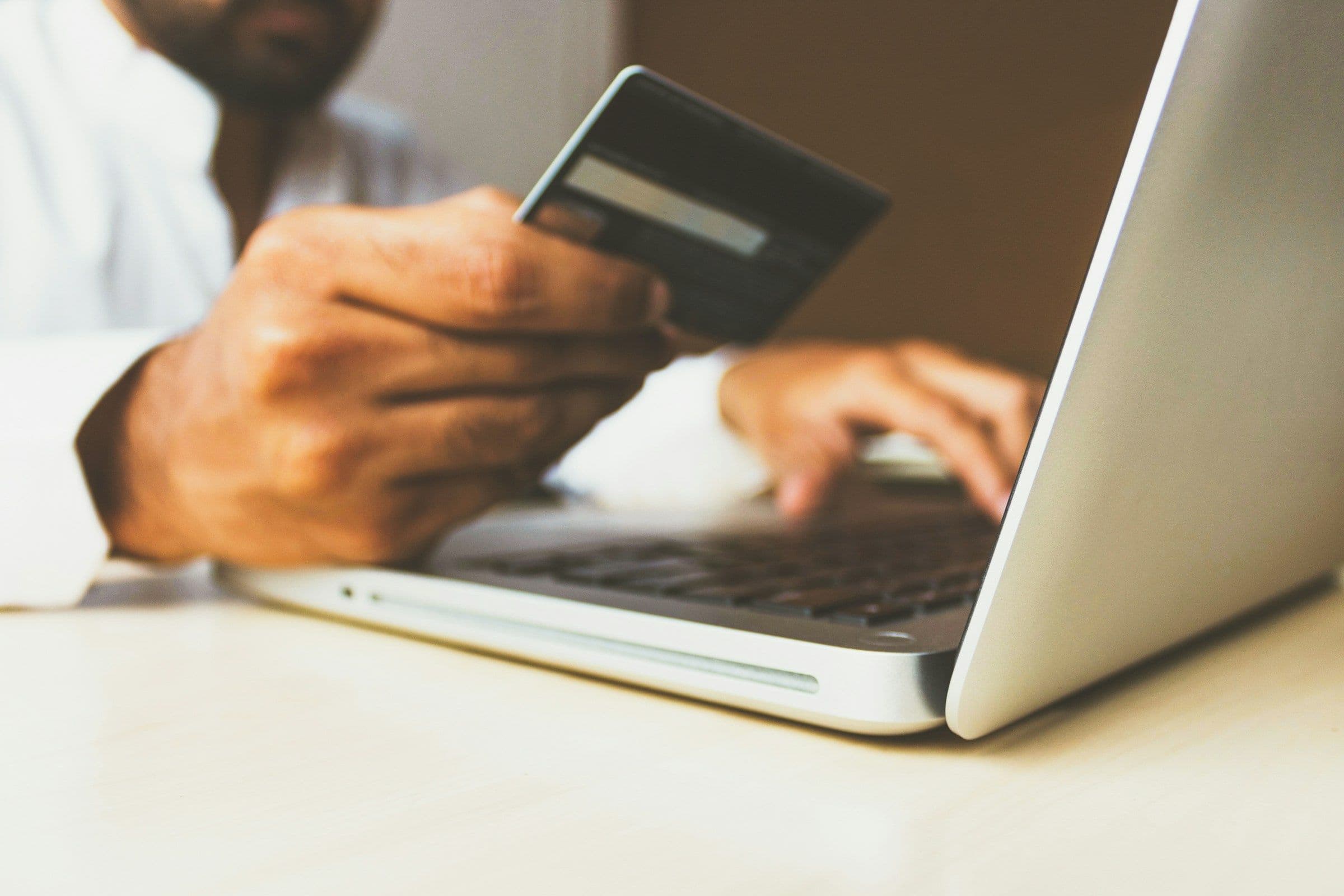 Customer holding a payment card while shopping on a laptop