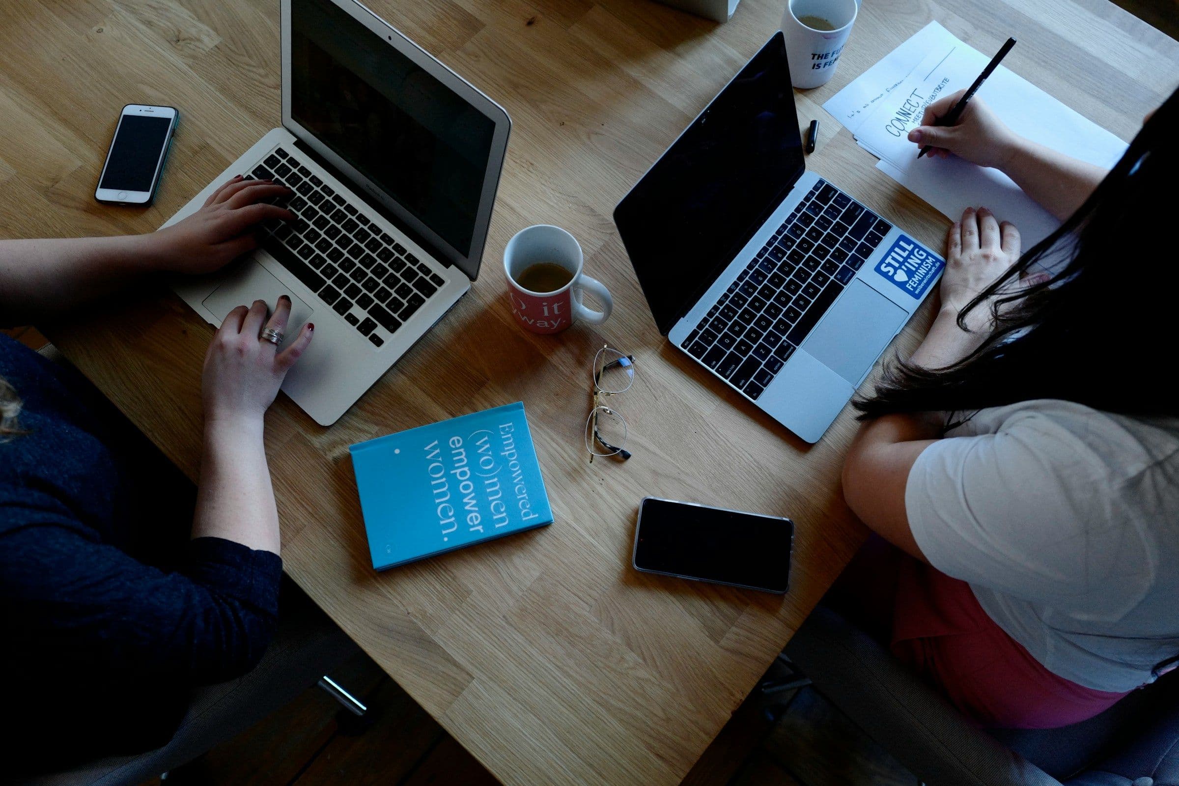Two support operators comparing customer information on laptops at a shared table