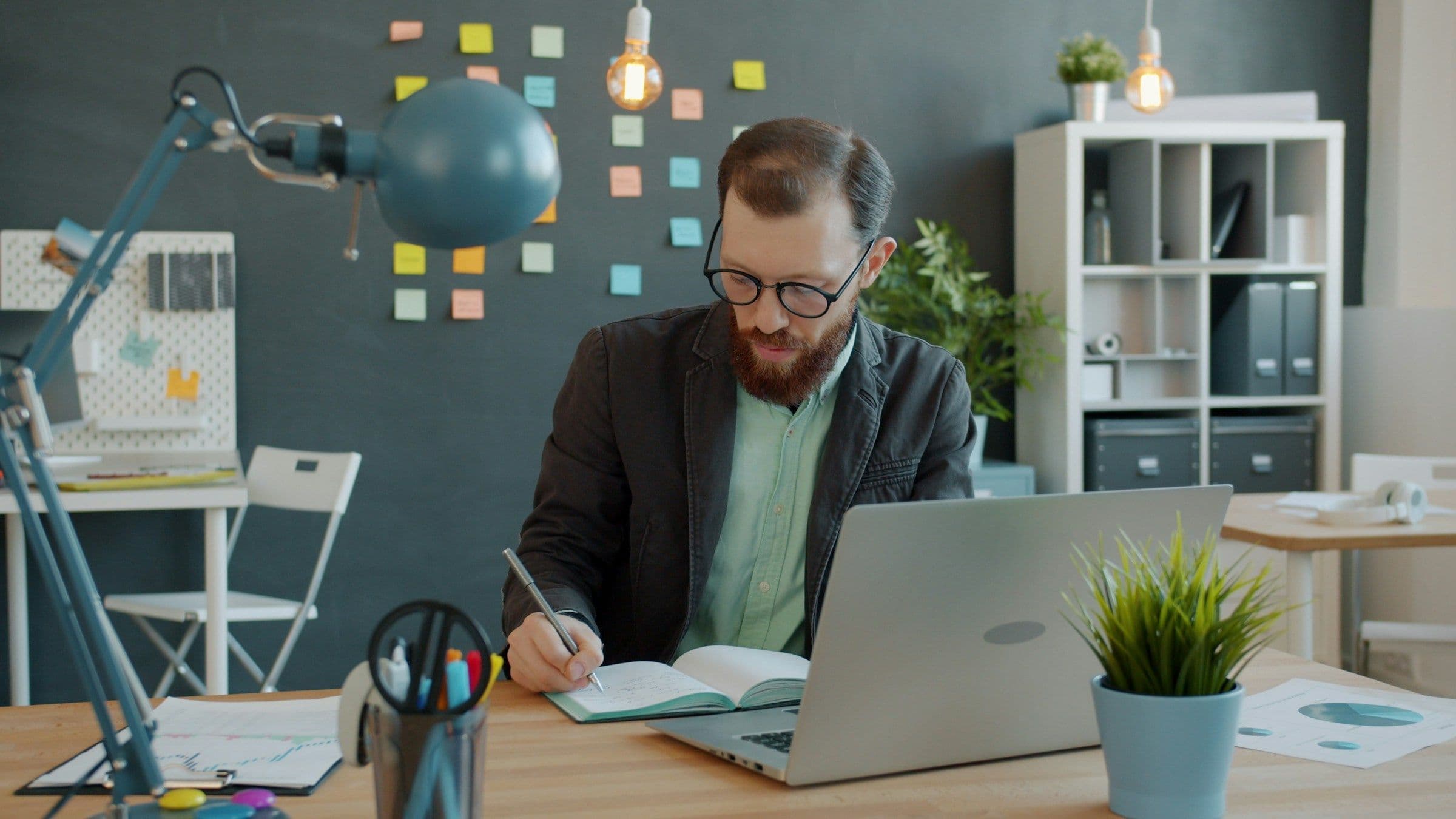 Operator reviewing charts and writing a launch plan beside a laptop