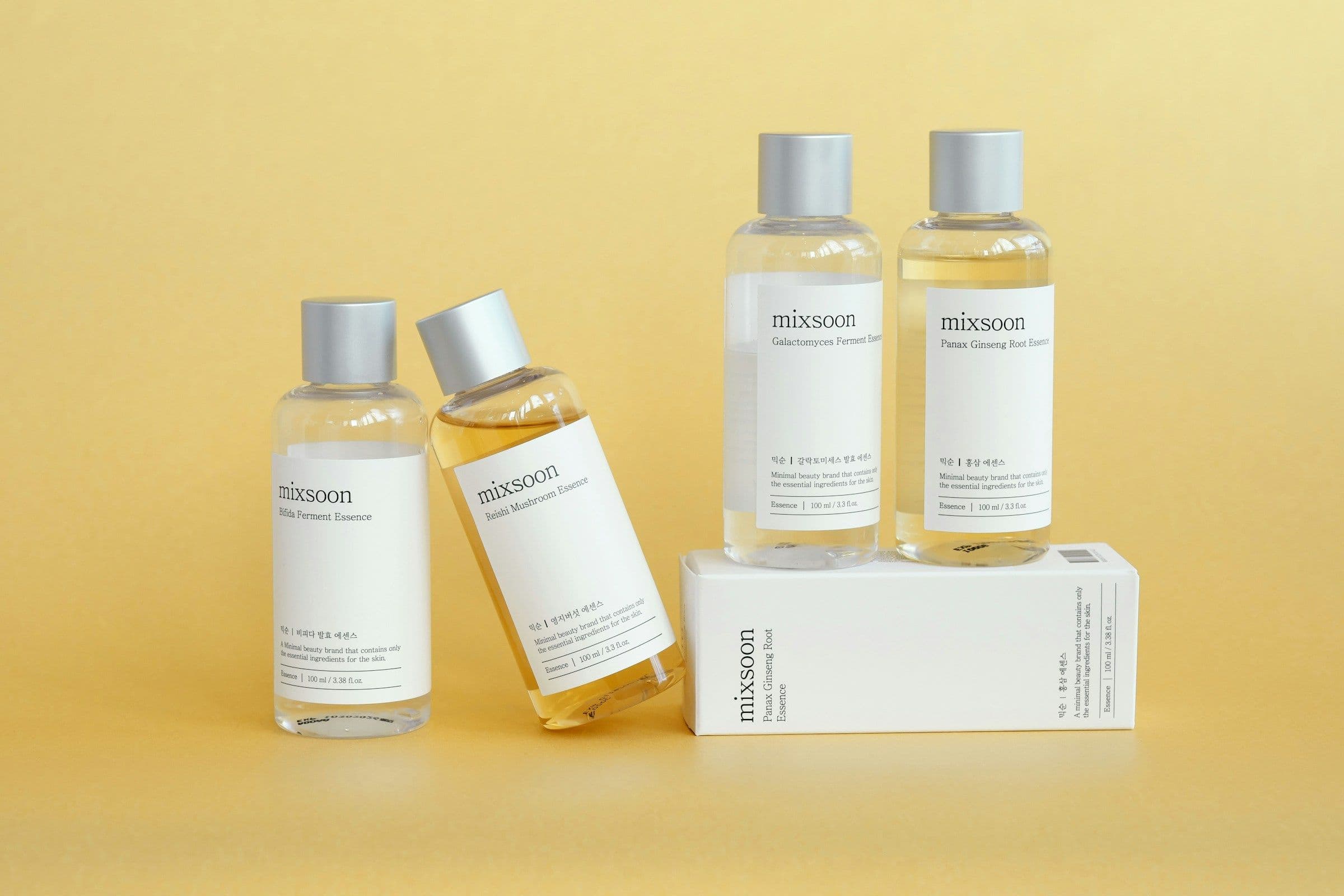 Korean skincare essence bottles arranged against a yellow background